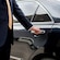 A professional driver in a suit opening the rear door of a luxury sedan